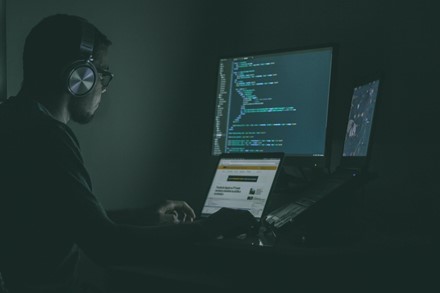 Man typing, coding and wearing headset