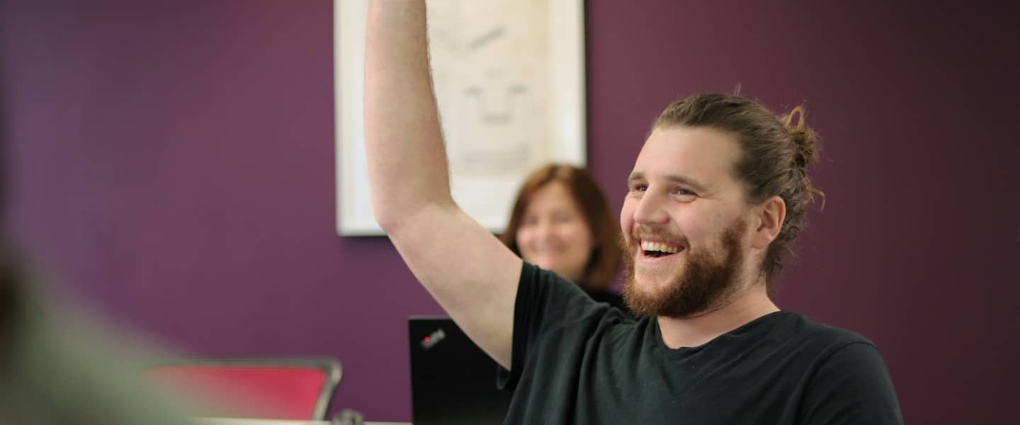 Person raising hand to answer, smiling